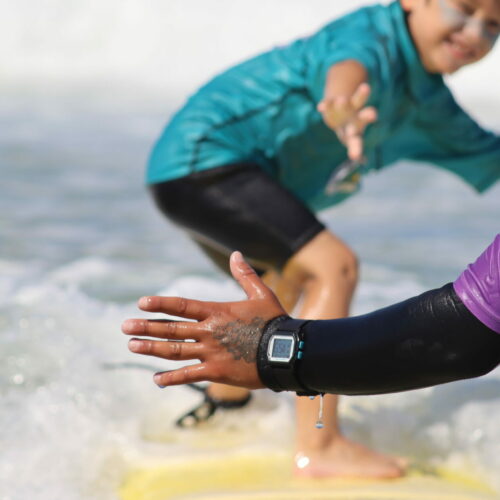 Photo d'un élève sur une planche de surf qui prend des cours